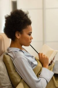 a woman on the bed holding a pencil and notebook thinking