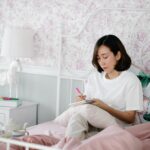 woman sitting in bed and writing