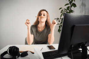 Woman at a desk balancing a pencil between her nose and top lip.