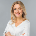 Lady with long blonde hair in a white shirt holding glasses