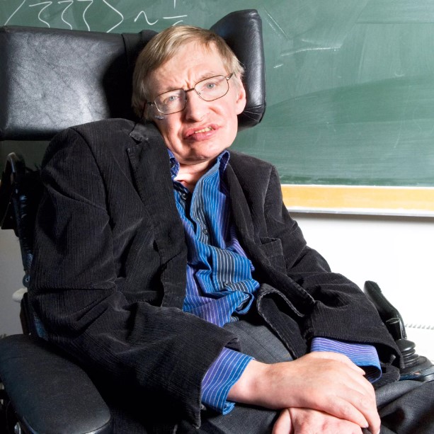 Stephen_Hawking Stephen Hawking sitting in a chair in front of a green chalk board.