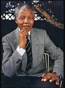 Nelson Mandela in a grey suit with black and silver striped tie with his hand against his chin.