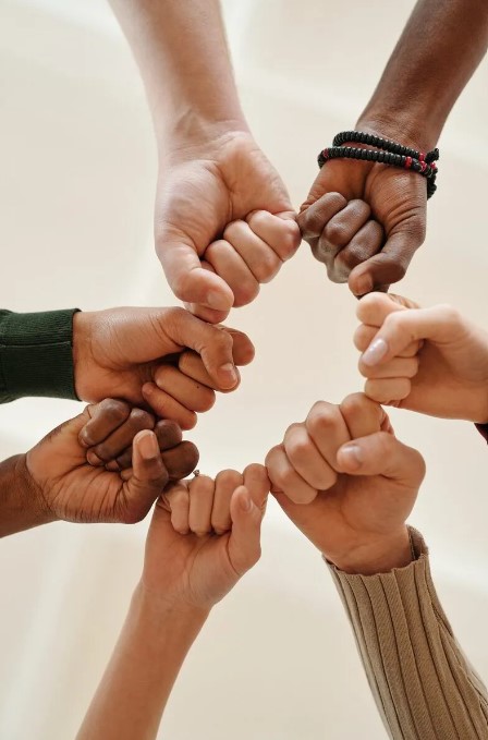 Looking up at 7 different clenched human fists all together creating a circle.