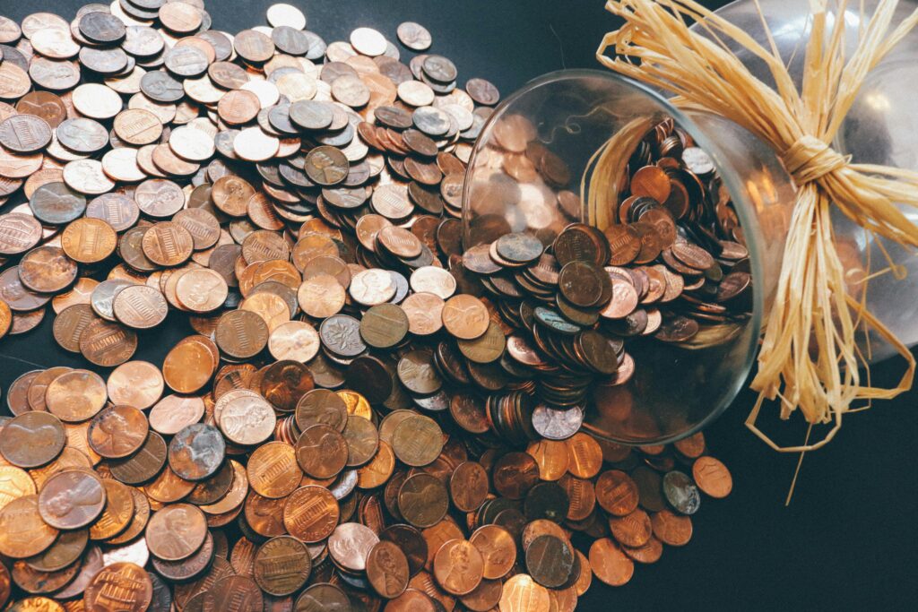 Spilled jar of pennies creating a pattern of coins representing savings and finance.