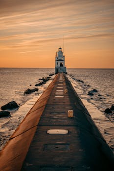Stunning sunset view of the Manitowoc Breakwater Lighthouse, WI, capturing the tranquil ocean and warm skies.