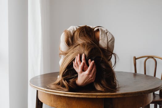 A woman showing despair with her head down on a table, indicating burnout.